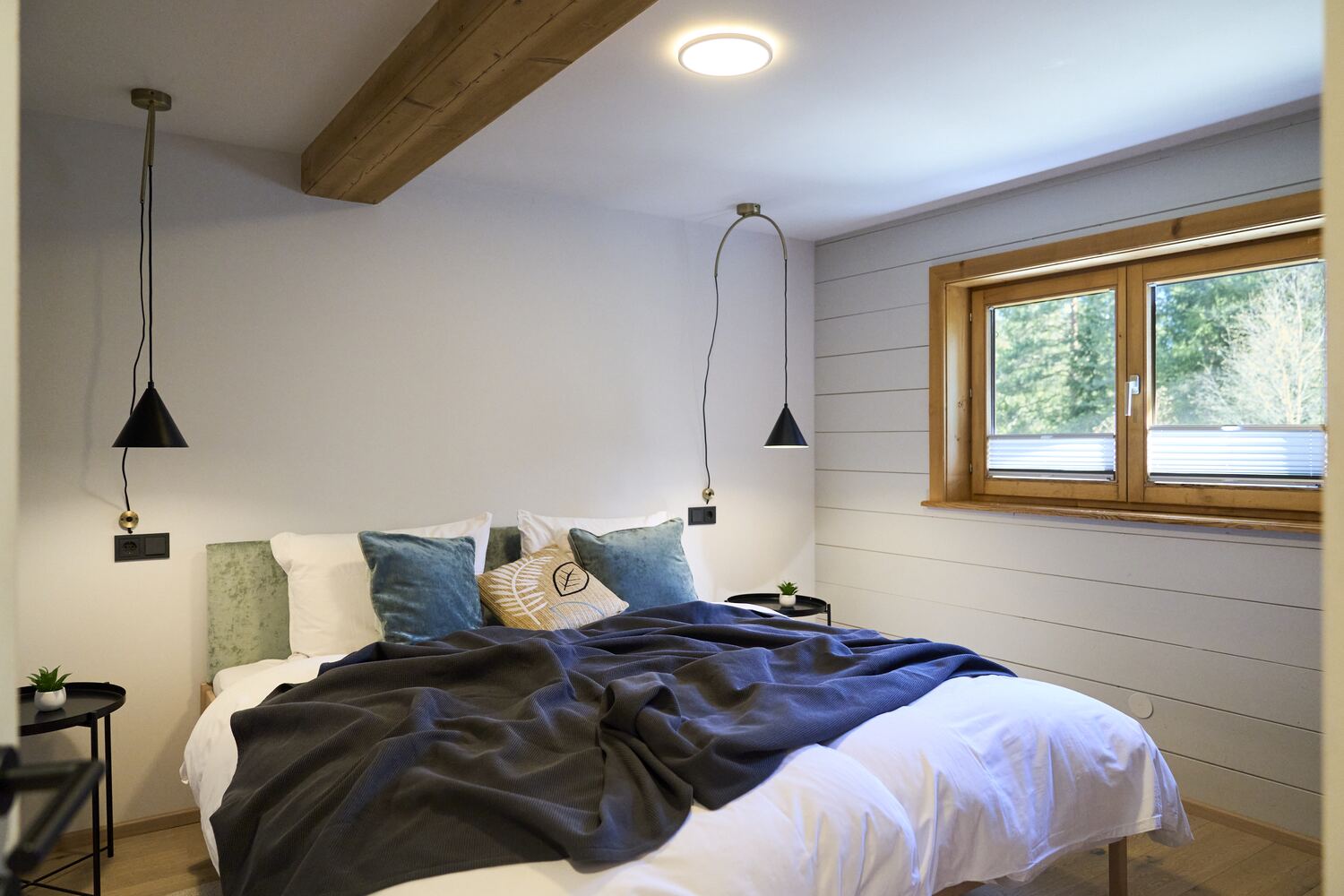 Camera da letto luminosa con lampade a sospensione e finestra sul verde