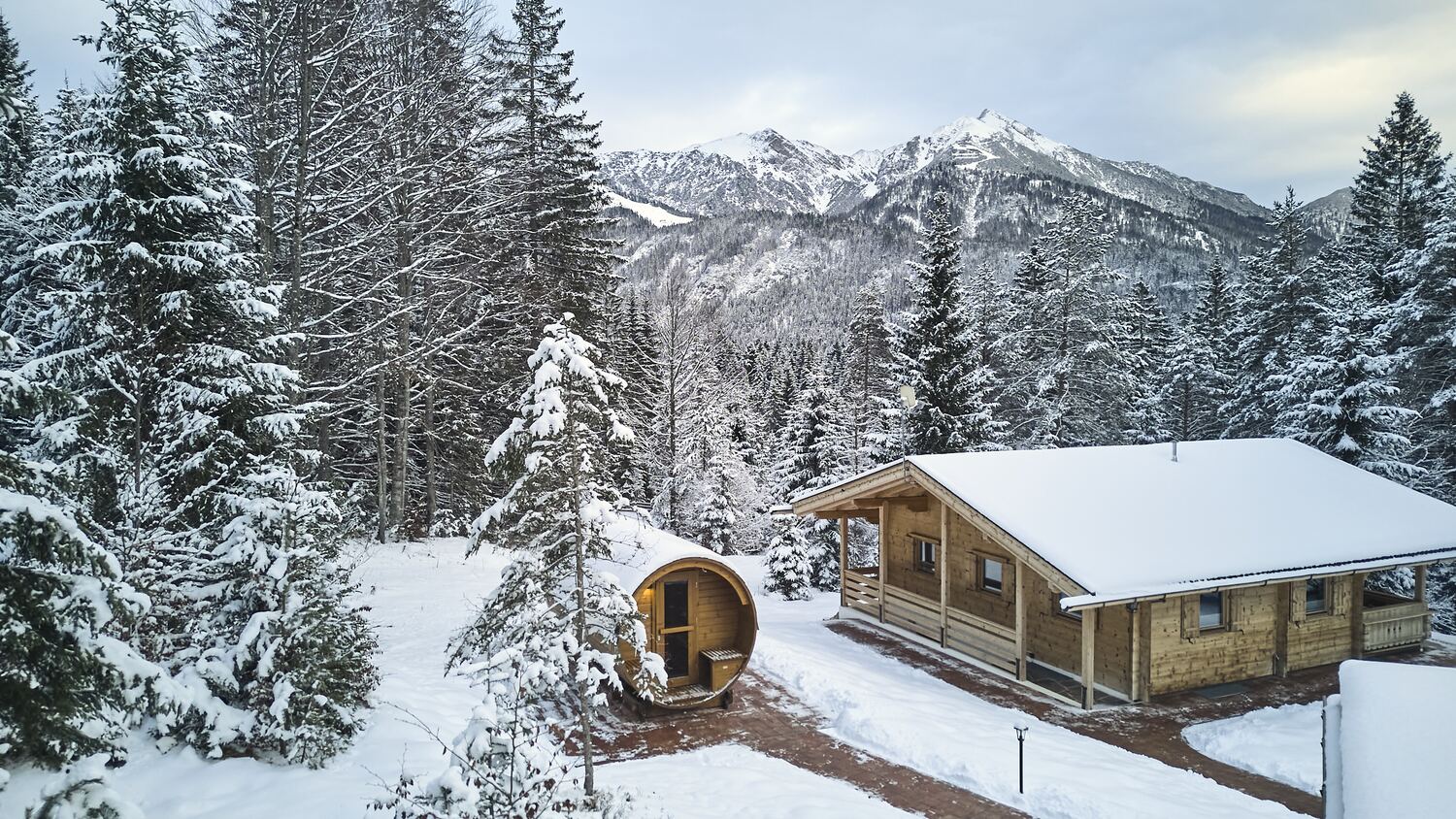 Chalet e sauna a botte sotto una spessa coltre di neve ai margini del bosco